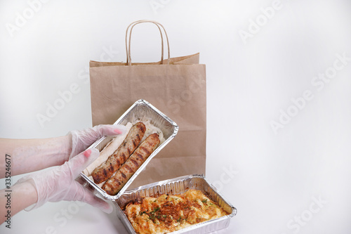 Delicious food in foil boxes, food delivery in a paper bag.
