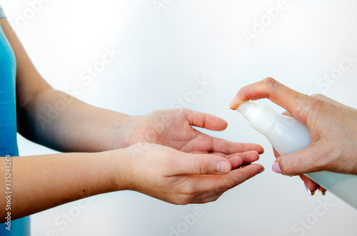 Disinfect your hands with a disinfectant and destroy the viruses on your hands. A female hand with a spray bottle with a disinfectant sprays the product on the hands of a child. The concept of