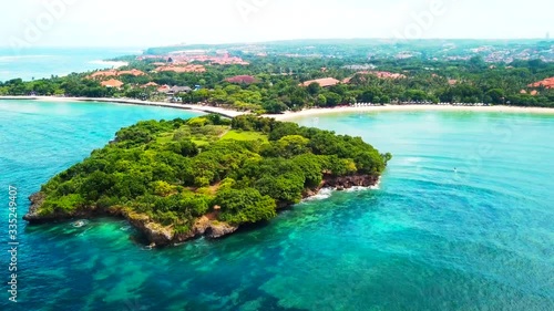 Nusa Dua Bali aerial footage forward dolly shot and flight over Nusa Dharma peninsula above beach bay area in Indonesia viewed from above during summer afternoon in the peak of the tourist season photo