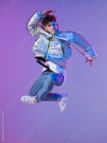 Cool guy dancing contemporary dance in studio. Neon light background. Acrobatic bboy dancer. Break dance lessons.