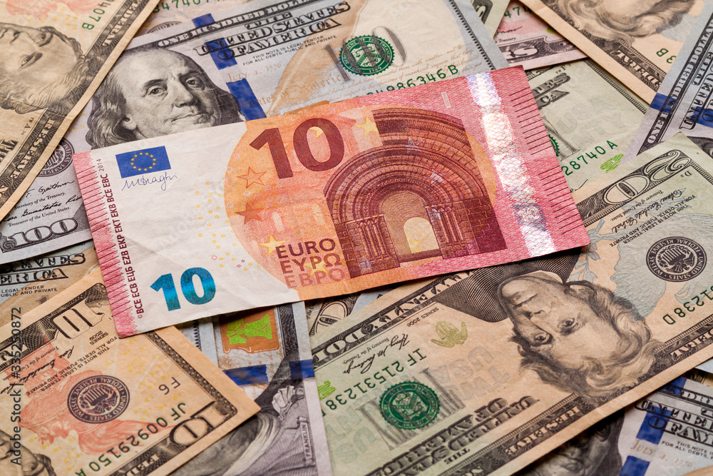 Money and finances concept. Ten euro new bill on colorful abstract background of American national currency, dollar banknotes. Money and finances concept. Ten euro new bill on colorful abstract background of American national currency, dollar banknotes.