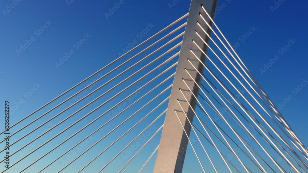 White pylon and cables of a cable-stayed bridge Millennium in Podgorica Montenegro, on a sunny afternoon, against clear blue sky. Aerial footage.