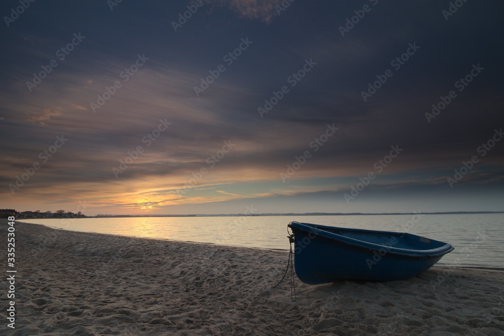 A boat on the beach during sunset.