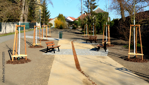 Newly Established Park Beige Gravel Road Metal Design Bar Benches and Ornamental Trees with Shingle Granite Tiles paving pavement photo