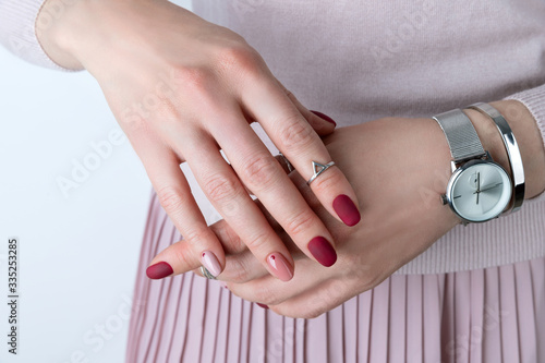 Womans hands with silver jewelry and accessories. Girl with minimal pink spring summer manicure design. photo