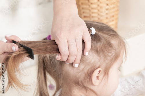 mother hands combing a comb little three-year-old girl