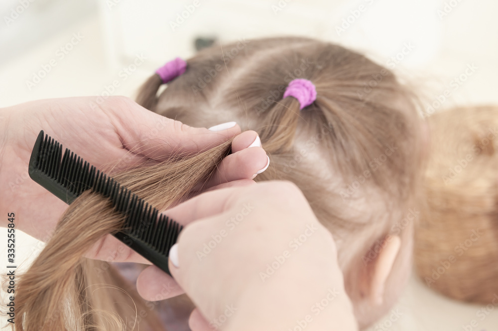 Fototapeta premium mother hands combing a comb little three-year-old girl