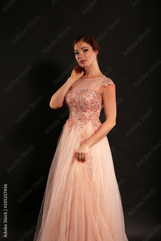 Pretty woman wearing pink dress on black background