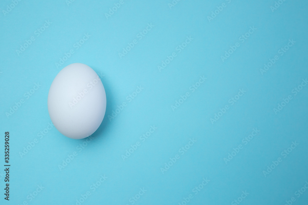 Fresh white egg on blue surface stock photo