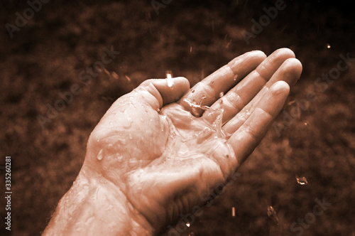 Man hand catching water drops of rain climate change