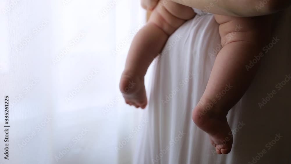 Mom holds in her arms a small child standing near the window Mom holds in her arms a small child standing near the window