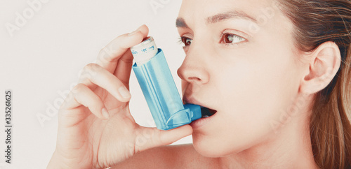 Young woman using inhaler during asthmatic attack at home, closeup, white background