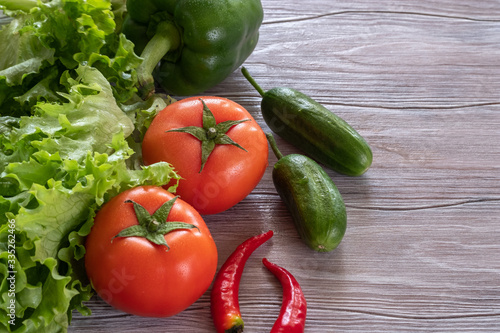 Fresh, juicy green and red vegetables on a wooden table