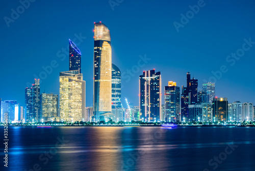 Beautiful City night view of Abu Dhabi financial and commercial district, taken during blue hour, view from marina backwater, United Arab Emirates, luxury life style, business in UAE,