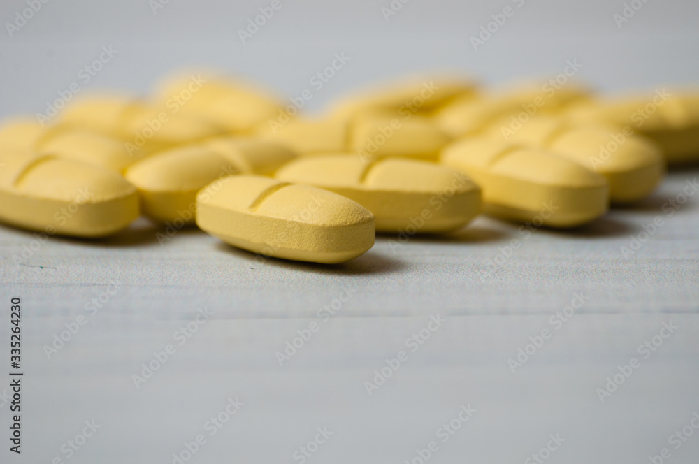 A lot of yellow pills close-up macro on a light wooden table. There is a place for text A lot of yellow pills close-up macro on a light wooden table. There is a place for text