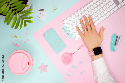 Business flat layout on colorful background. Palm leaf, hand on keyboard, cup and accessories