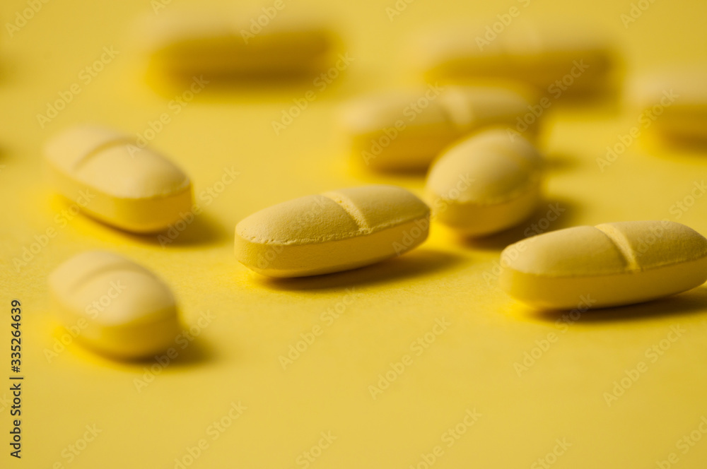 Medical pills or vitamins on a yellow background macro closeup Medical pills or vitamins on a yellow background macro closeup