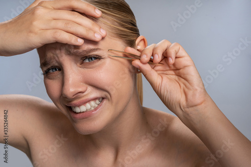 Emotional blonde female person doing eyebrows correction