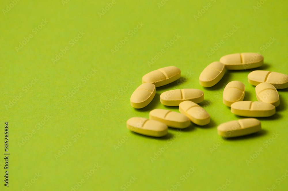Many yellow pills on a green background with room for copy space Many yellow pills on a green background with room for copy space