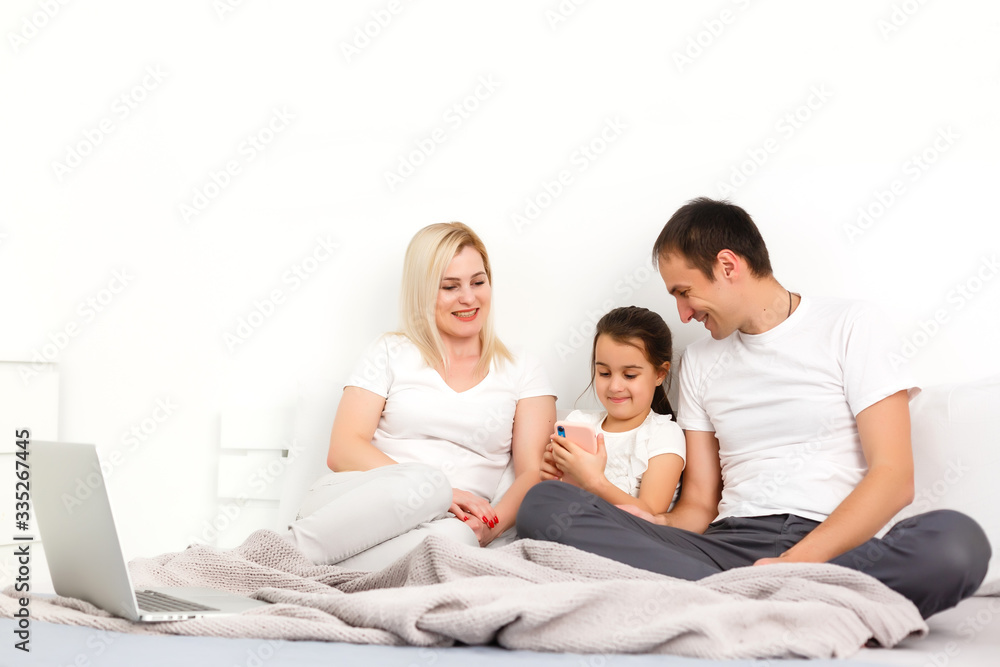 Happy family lies on bed and watching something on laptop. Happy family lies on bed and watching something on laptop.