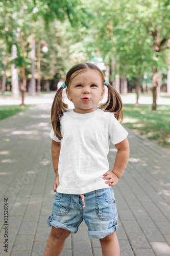 smiling little girl in blank white t-shirt standing in park