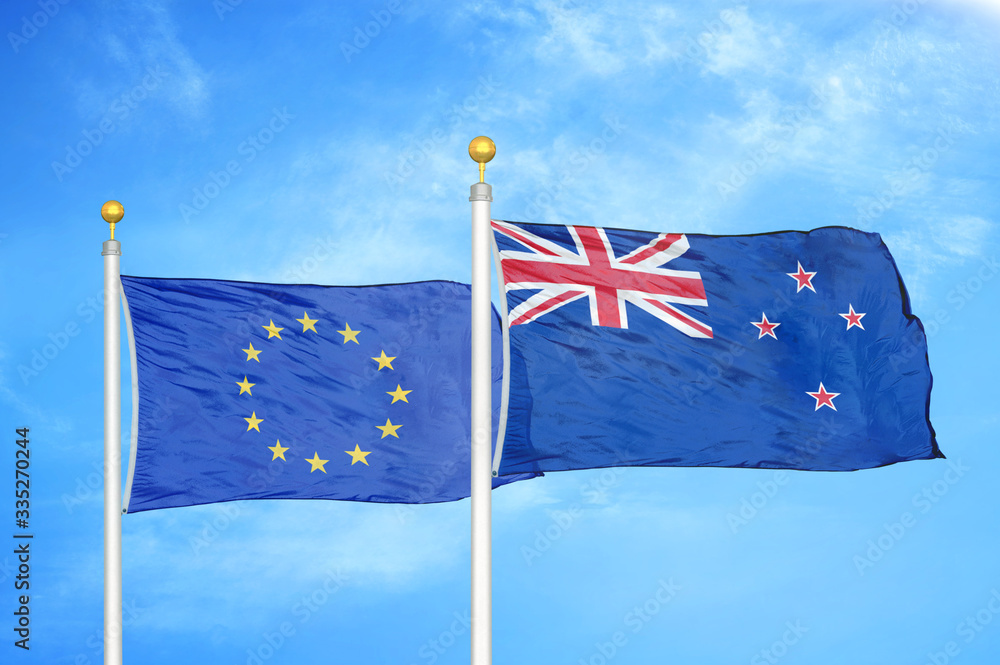 Fototapeta premium European Union and New Zealand two flags on flagpoles and blue cloudy sky