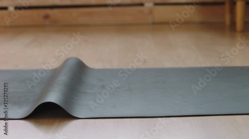 Fit young adult Caucasian female unrolling yoga mat before yoga practice at home. Stay home, quarantine workout. Shot on ARRI Alexa Mini