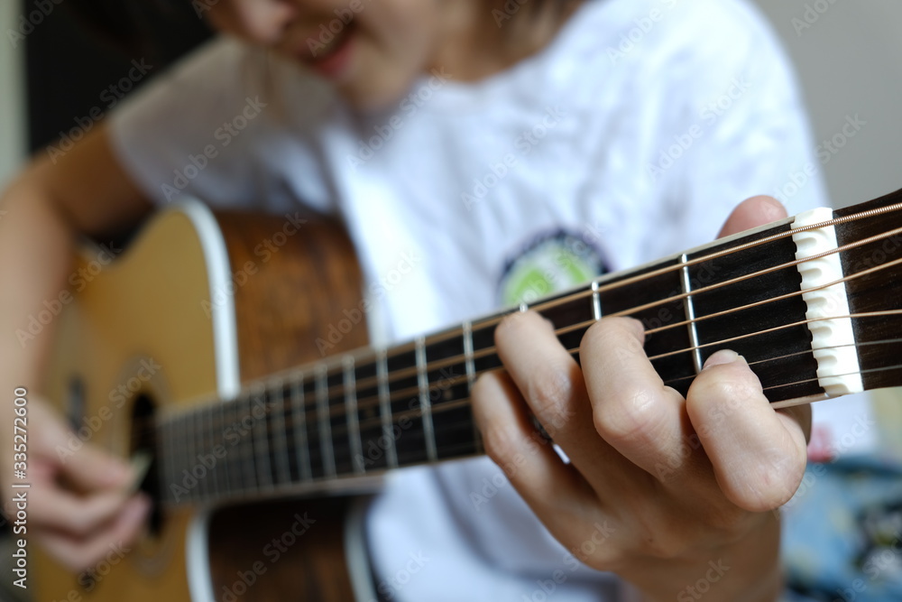 A lady plays guitar. Focus on index finger.
