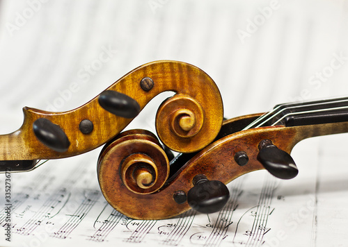 Two violins on a  sheet music background. Violin heads