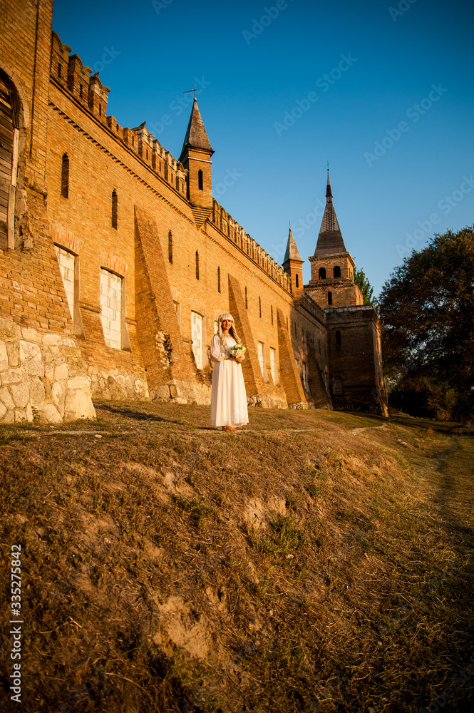 blonde girl in a white dress on nature near architectural monuments in the open air