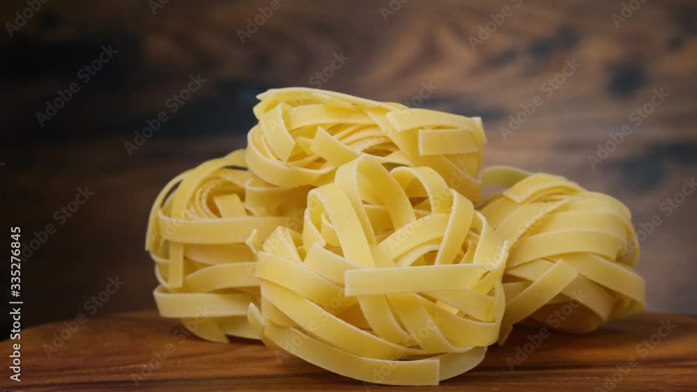 Rotating fettuccine pasta on wooden background Rotating fettuccine pasta on wooden background