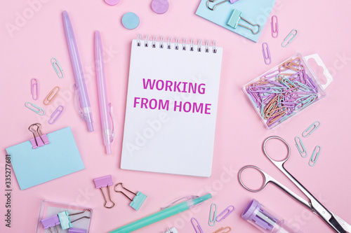 Home office workplace with notebook and pastel colorful study accessories on pink background. Working from home concept