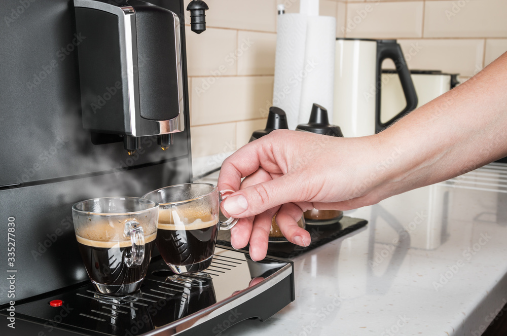 woman's hand takes a glass Cup of hot coffee from the coffee machine woman's hand takes a glass Cup of hot coffee from the coffee machine