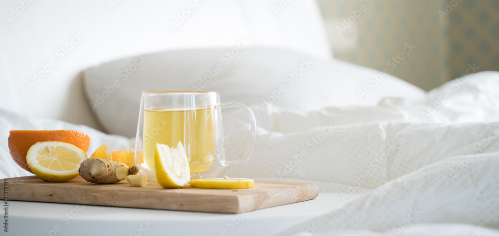 Cup with antipyretic drugs for colds,flu.Tea with citrus vitamin C,ginger root,lemon,orange.Wooden tray in patient's bed. Home self-treatment.Medical quarantine antiviral covid-19 coronavirus therapy Cup with antipyretic drugs for colds,flu.Tea with citrus vitamin C,ginger root,lemon,orange.Wooden tray in patient's bed. Home self-treatment.Medical quarantine antiviral covid-19 coronavirus therapy