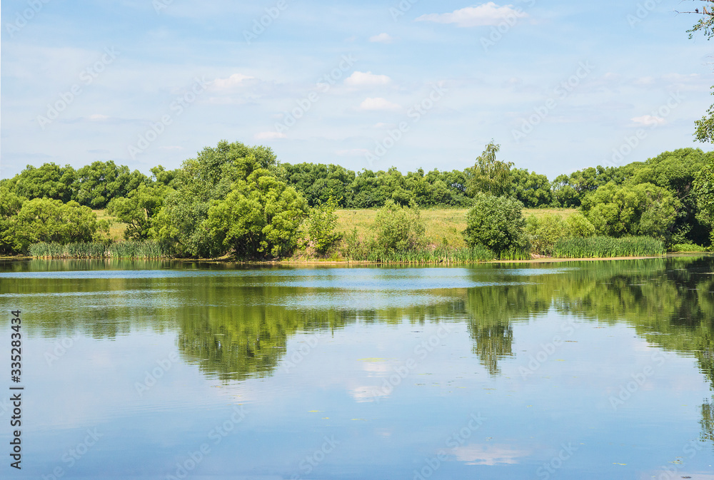 Beautiful summer landscape with pond and green bush. Reflection in water Beautiful summer landscape with pond and green bush. Reflection in water