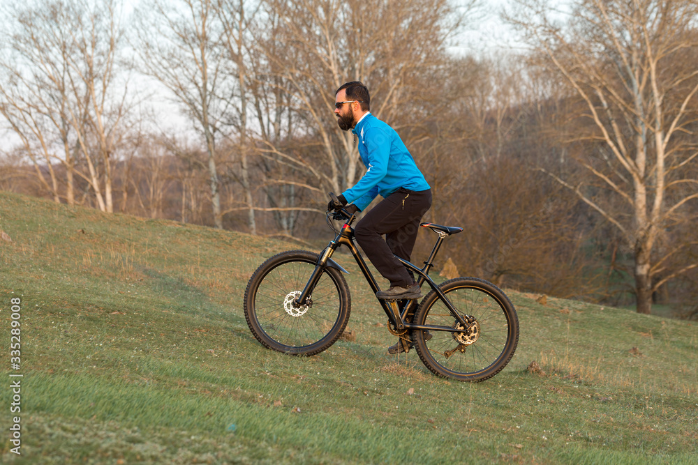 Cyclist in pants and fleece jacket on a modern carbon hardtail bike with an air suspension fork. The guy on the top of the hill rides a bike. Cyclist in pants and fleece jacket on a modern carbon hardtail bike with an air suspension fork. The guy on the top of the hill rides a bike.