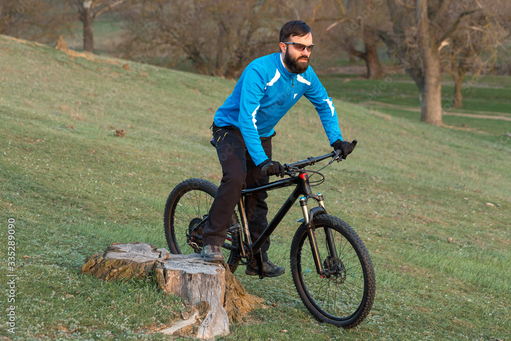 Obraz premium Cyclist in pants and fleece jacket on a modern carbon hardtail bike with an air suspension fork. The guy on the top of the hill rides a bike.