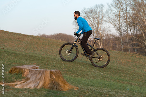 Cyclist in pants and fleece jacket on a modern carbon hardtail bike with an air suspension fork. The guy on the top of the hill rides a bike.