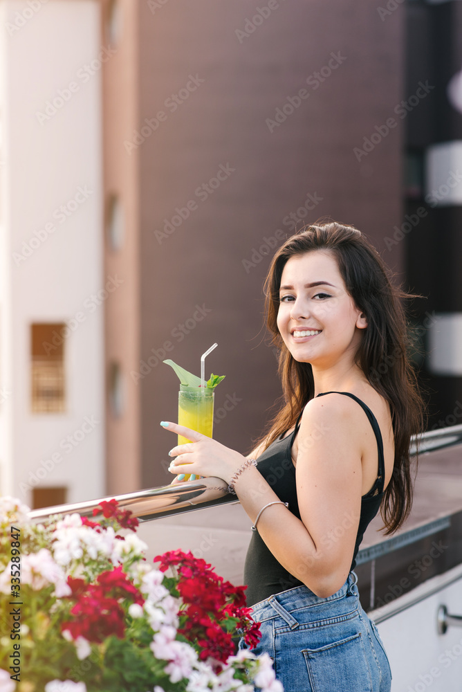 Pretty girl with yellow cocktail relaxing on the balcony with beautiful view Pretty girl with yellow cocktail relaxing on the balcony with beautiful view