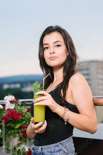 Pretty girl with yellow cocktail relaxing on the balcony with beautiful view