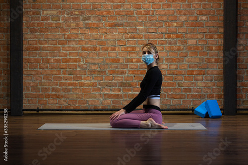 Young russian girl in yoga pose in medical mask