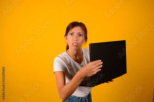 technology woman with laptop with emotions on yellow background portrait technology