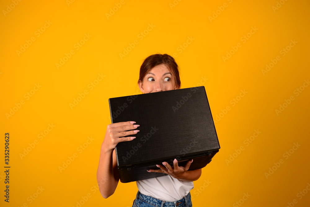woman with emotions holds laptop on a yellow background woman with emotions holds laptop on a yellow background