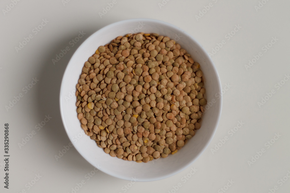 close-up of green lentil grits raw on a white plate on a light background. vegetarian food. close-up of green lentil grits raw on a white plate on a light background. vegetarian food.
