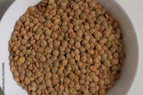 close-up of green lentil grits raw on a white plate on a light background. vegetarian food.