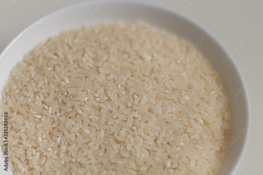 close-up of raw rice grits on a white plate on a light background. vegetarian food.