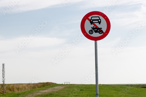 Traffic signs forbidden passage for cars and motorcycles on the edge of a meadow.