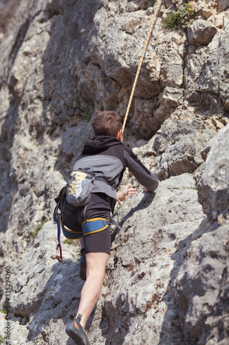 A teenager on a rock is engaged in rock climbing, children's sports in nature, outdoor activities for children