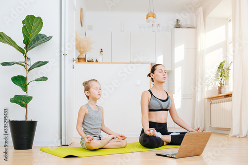 Fototapeta Naklejka Na Ścianę i Meble -  Mom and son doing yoga, sitting in a lotus asana, meditating