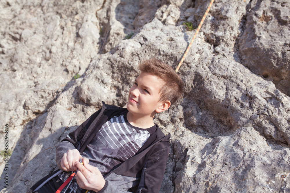 A teenager on a rock is engaged in rock climbing, children's sports in nature, outdoor activities for children